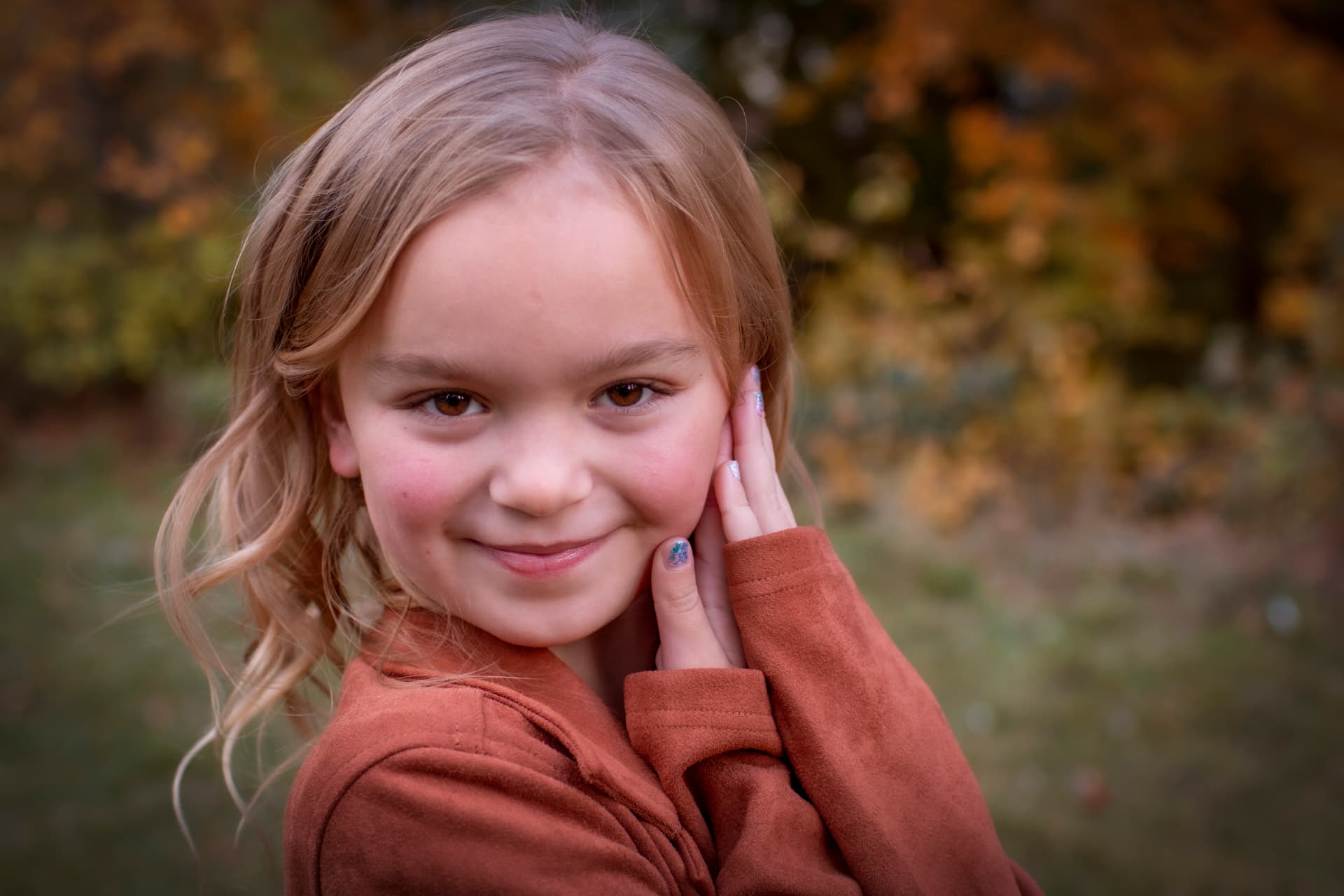 Young girl in a rust-colored sweater smiling