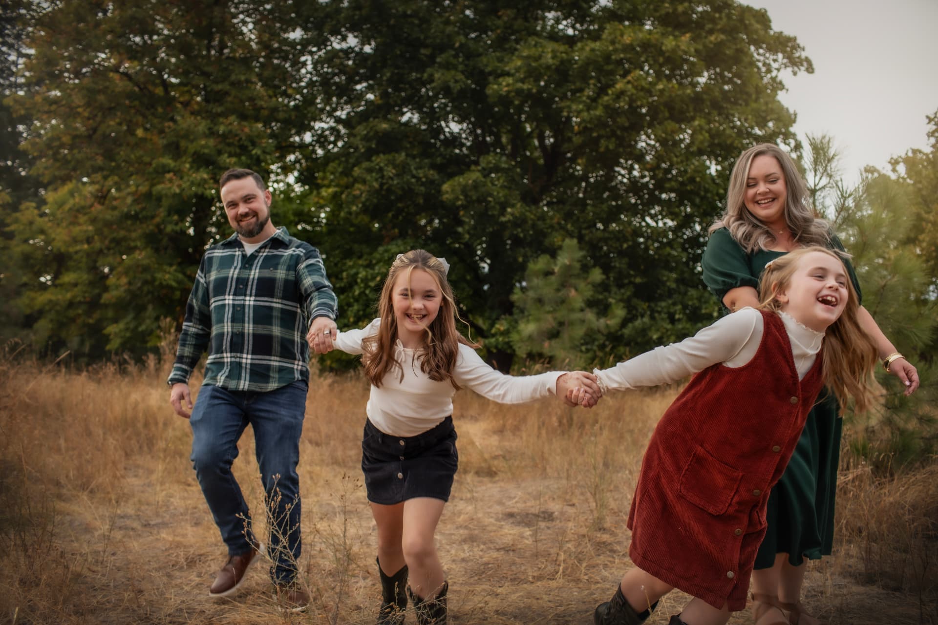 Family running hand in hand through an autumn field