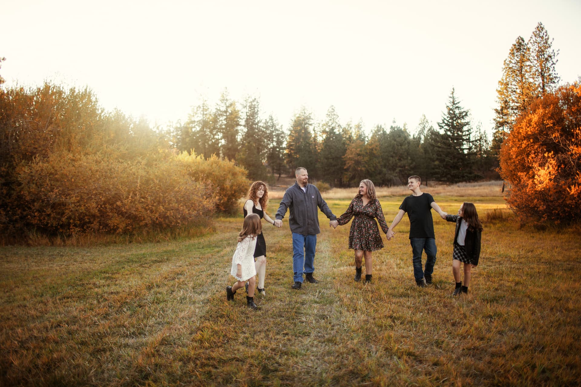 Family holding hands walking through a golden field
