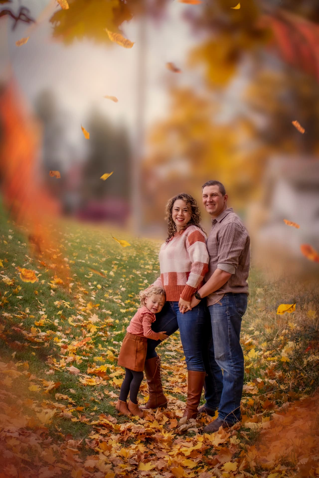 Family of three under falling autumn leaves